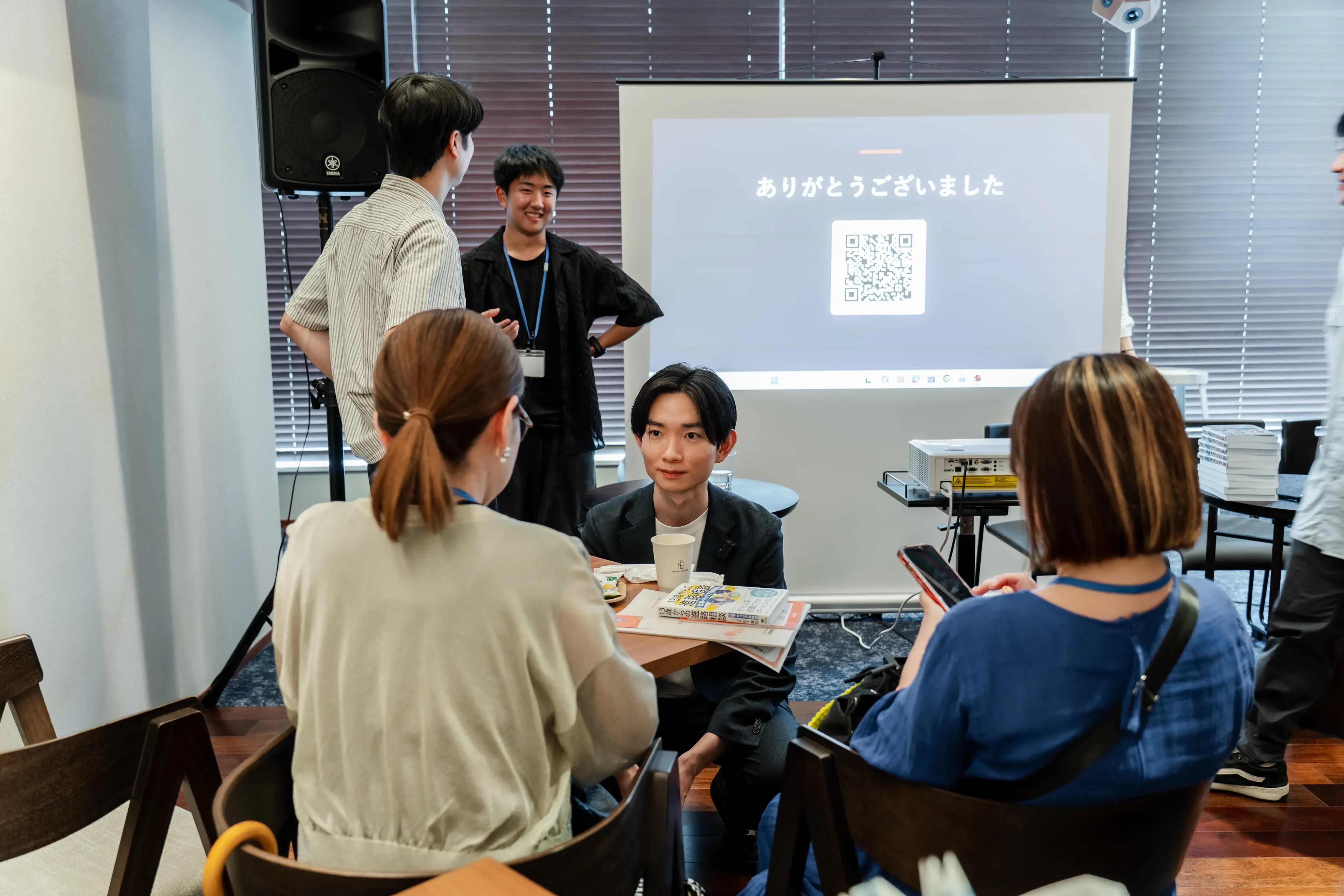 ありがとうございましたのスクリーン前でしゃがんで参加者と話す松下雅征